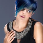 Mujer con cabello azul y un collar, reflejando su personalidad vibrante y original.