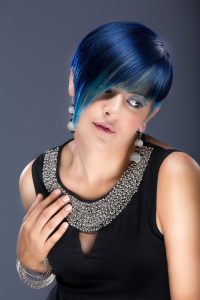 Mujer con cabello azul y un collar, reflejando su personalidad vibrante y original.