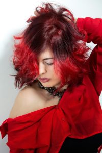 Mujer de pelo rojo adornada con un collar, capturada en un momento de calma y elegancia.