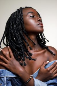 Una mujer con un peinado trenzado que cubre toda la cabeza, mostrando su cabello largo con un diseño intrincado y elegante.